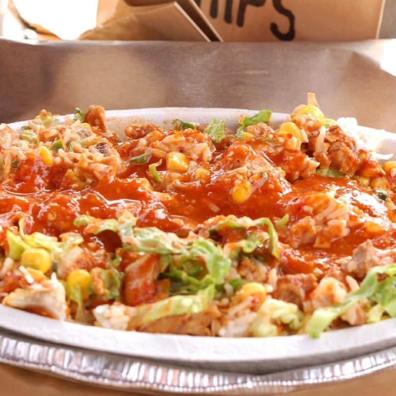 A photographed burrito bowl with chicken, rice, black beans and cheese